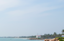 A tranquil sandy beach with wooden fishing boats, rocky outcrops, and calm turquoise waters — a perfect destination for day trips from Pondicherry thumbnail