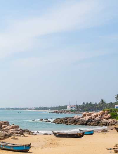A tranquil sandy beach with wooden fishing boats, rocky outcrops, and calm turquoise waters — a perfect destination for day trips from Pondicherry thumbnail