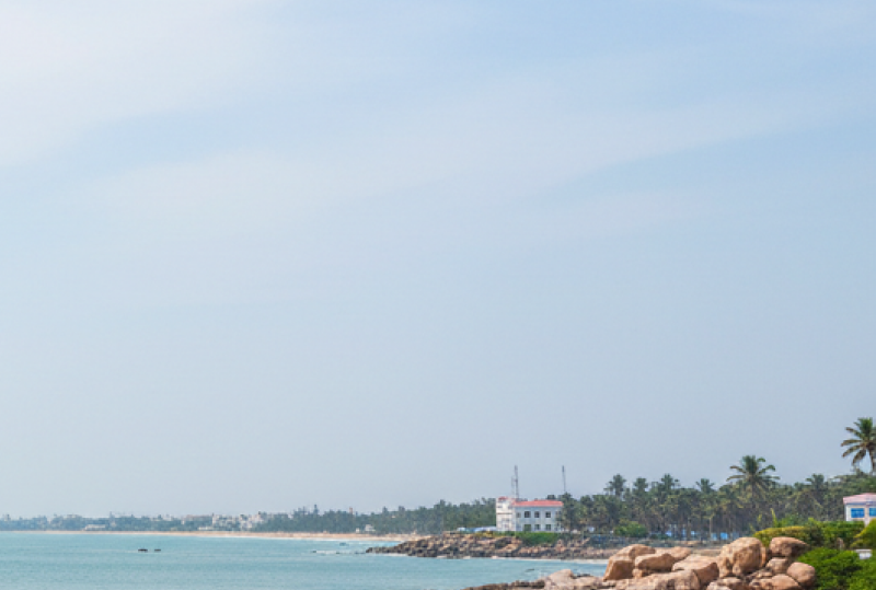 A tranquil sandy beach with wooden fishing boats, rocky outcrops, and calm turquoise waters — a perfect destination for day trips from Pondicherry thumbnail