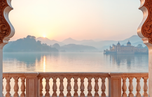 Ornate marble balcony overlooking a misty lake and palace at sunrise — one of the must visit places in India, Udaipur's Lake Palace, Rajasthan thumbnail