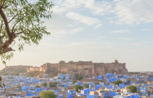 Panoramic view of Jodhpur's blue city and Mehrangarh Fort framed by carved Rajasthani arches — a glimpse into the heart of religious places in Jodhpur. thumbnail