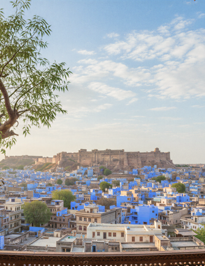 Panoramic view of Jodhpur's blue city and Mehrangarh Fort framed by carved Rajasthani arches — a glimpse into the heart of religious places in Jodhpur. thumbnail