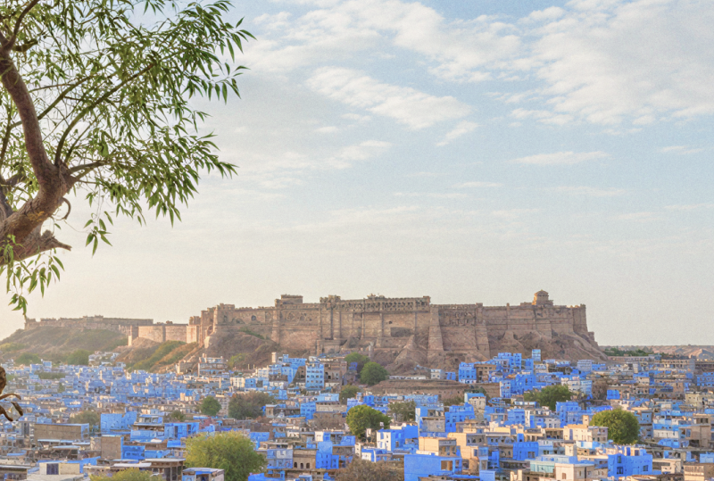 Panoramic view of Jodhpur's blue city and Mehrangarh Fort framed by carved Rajasthani arches — a glimpse into the heart of religious places in Jodhpur. thumbnail