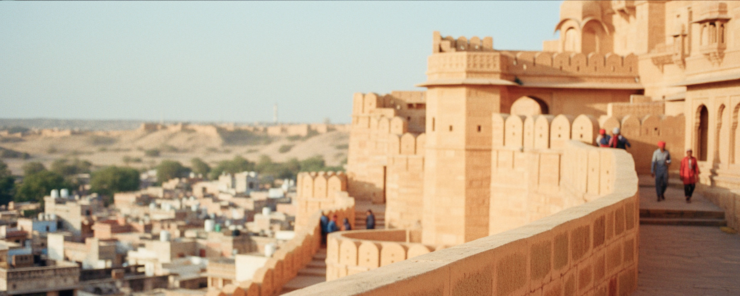 Visitors walking along the ramparts of Jaisalmer Fort, one of the most iconic historical places in India for tourists, overlooking the golden city below
