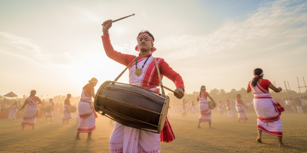 Dhol drummers and dancers in traditional red and white Assamese attire performing at the Rongali Bihu Festival of India
