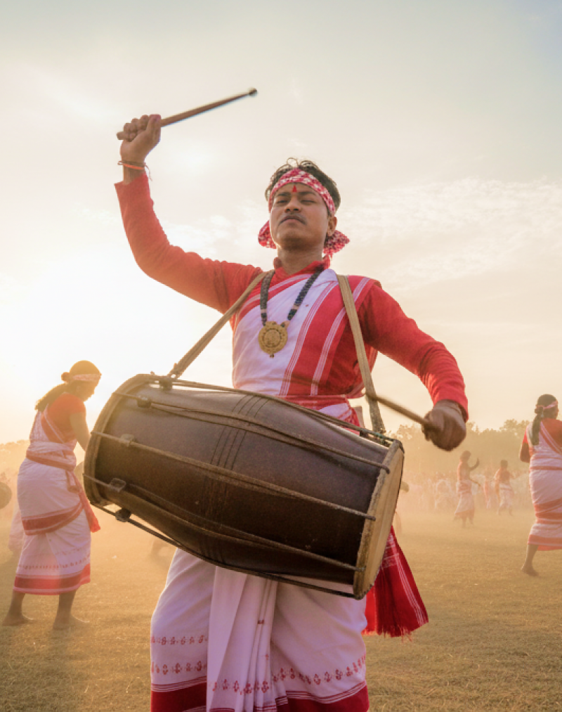 Dhol drummers and dancers in traditional red and white Assamese attire performing at the Rongali Bihu Festival of India thumbnail