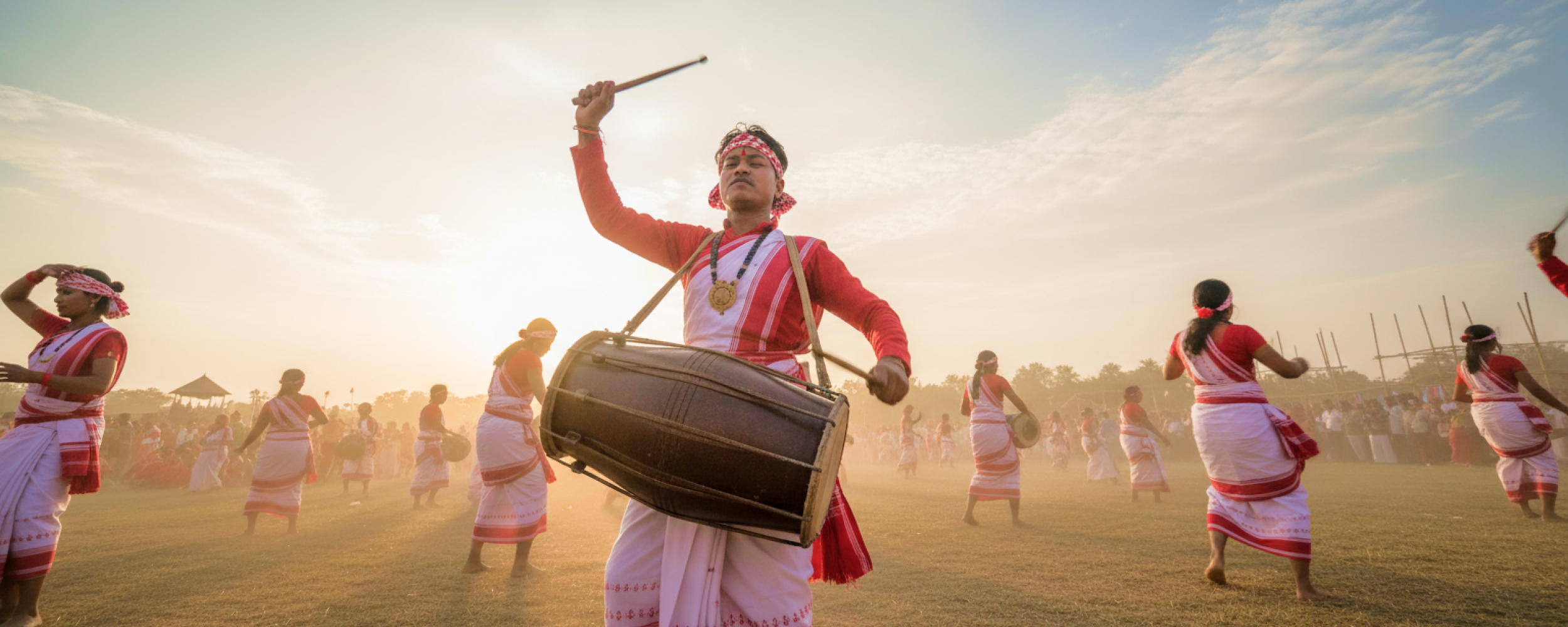 Dhol drummers and dancers in traditional red and white Assamese attire performing at the Rongali Bihu Festival of India
