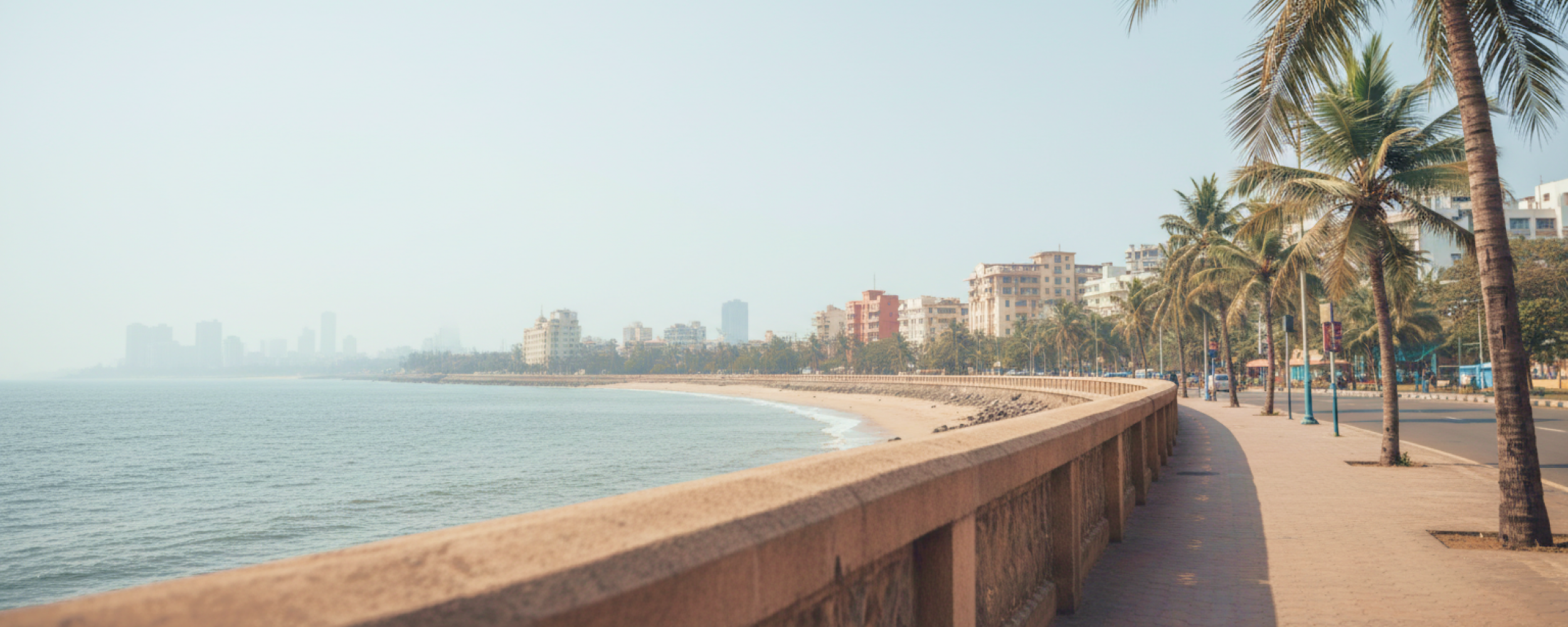 Marine Drive promenade on a Mumbai itinerary — palm lined seafront walkway with the Arabian Sea and city skyline in the background