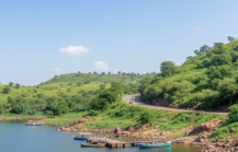 A calm blue lake surrounded by green hills with small boats docked near the shore, a scenic stop on a day Pune itinerary thumbnail