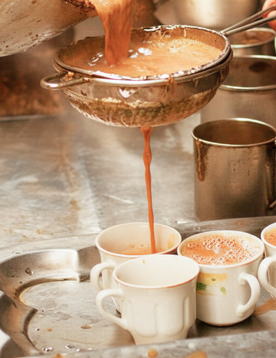 Traditional Kolkata chai being strained into cups at a tea stall