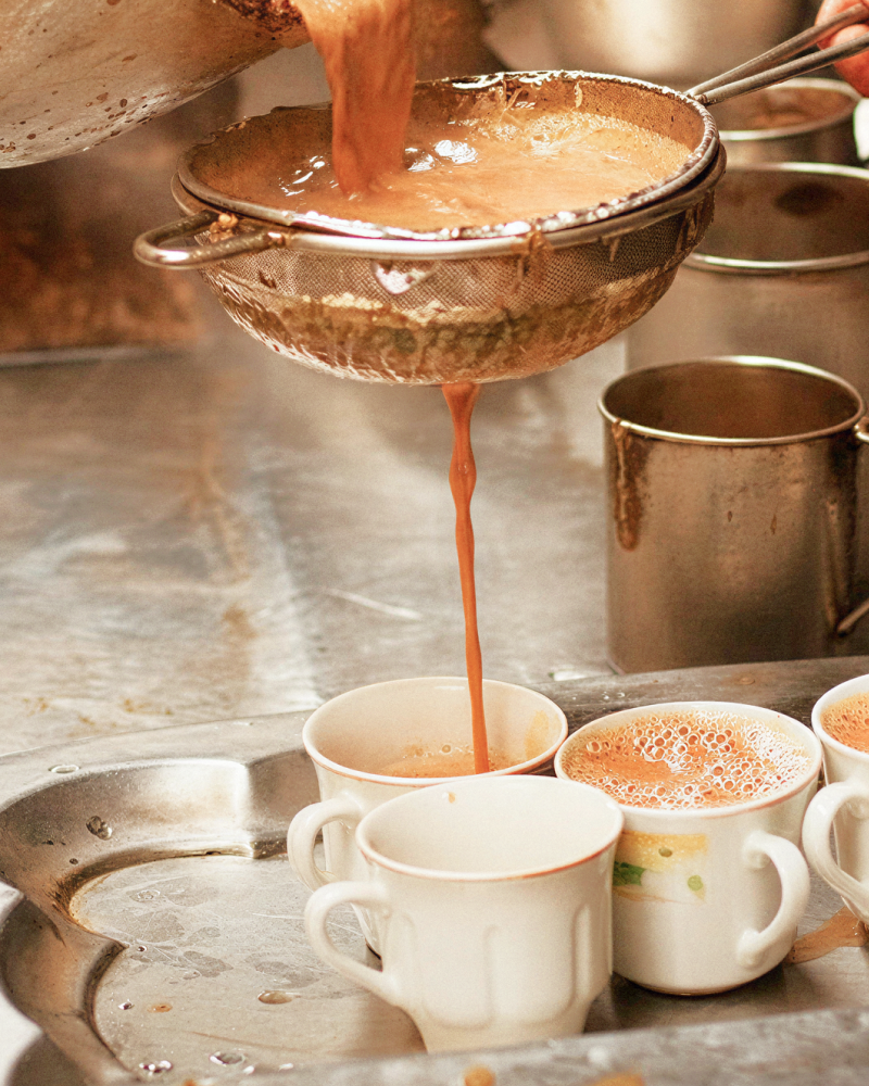 Traditional Kolkata chai being strained into cups at a tea stall