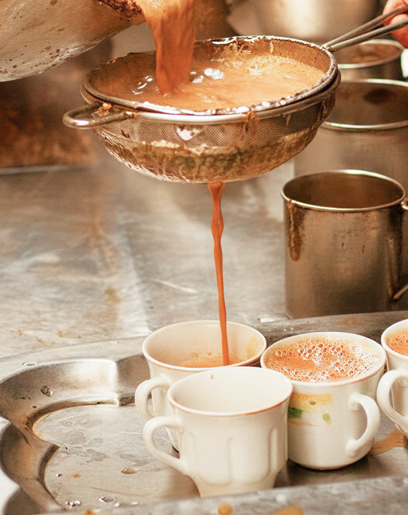 Traditional Kolkata chai being strained into cups at a tea stall