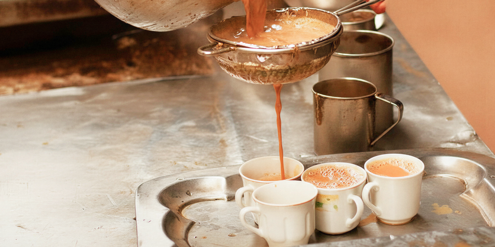 Traditional Kolkata chai being strained into cups at a tea stall