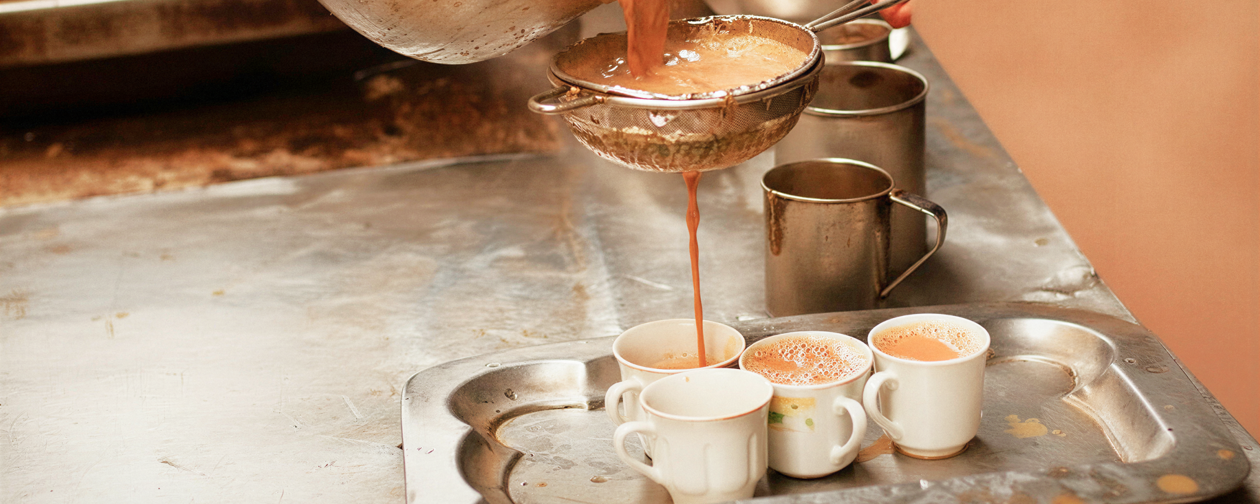 Traditional Kolkata chai being strained into cups at a tea stall