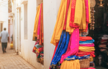 A colourful hidden shopping gem in Pondicherry — vibrant sarees and brass goods spilling out of a tiny stall tucked into a narrow whitewashed lane thumbnail