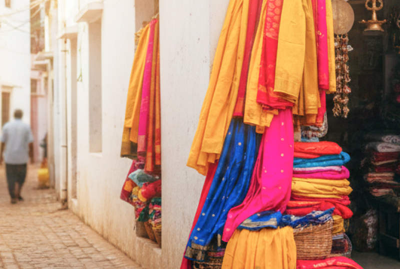 A colourful hidden shopping gem in Pondicherry — vibrant sarees and brass goods spilling out of a tiny stall tucked into a narrow whitewashed lane thumbnail