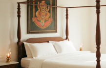 Charming stay in Pondicherry — a colonial four poster bedroom with white linen, Athangudi tiled floors, brass oil lamps, and a Tanjore painting above the bed thumbnail
