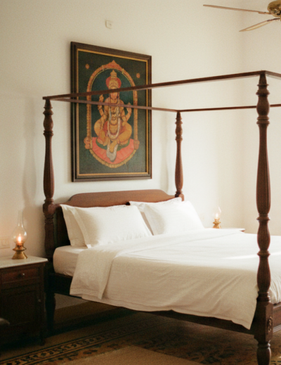 Charming stay in Pondicherry — a colonial four poster bedroom with white linen, Athangudi tiled floors, brass oil lamps, and a Tanjore painting above the bed thumbnail