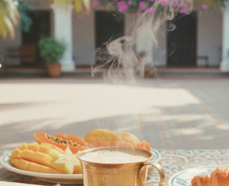 Pondicherry hotels and homestays experience — a colonial courtyard breakfast with steaming filter coffee, fresh tropical fruit, and a croissant on Athangudi tiled table thumbnail