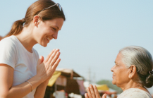 Cultural etiquette in India for tourists — traveler greeting a local woman with namaste at a colorful street market