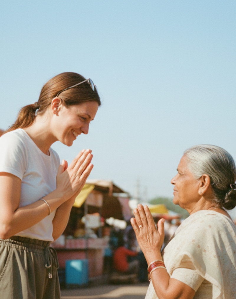 Cultural etiquette in India for tourists — traveler greeting a local woman with namaste at a colorful street market
