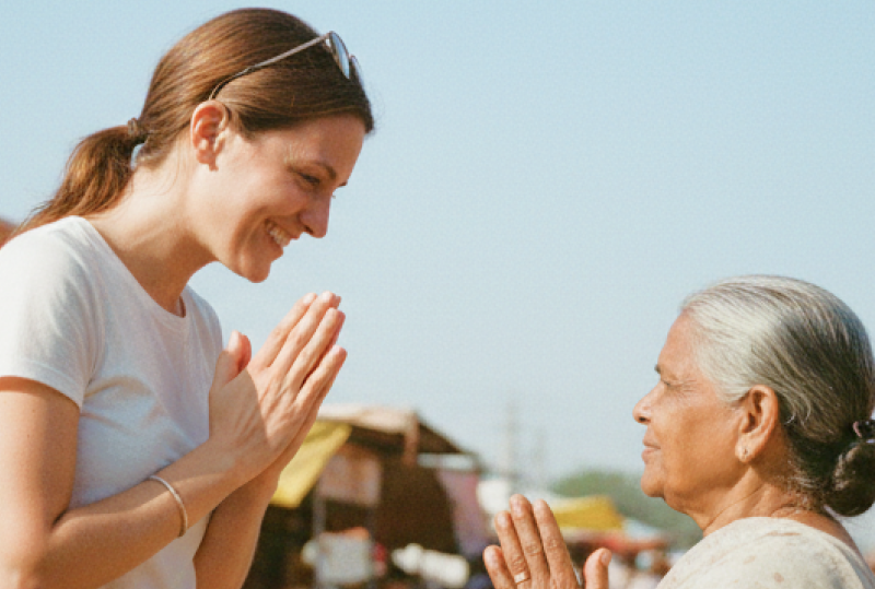 Cultural etiquette in India for tourists — traveler greeting a local woman with namaste at a colorful street market