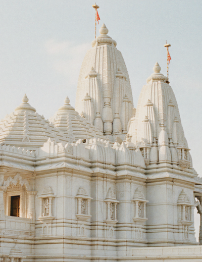 White marble Birla Mandir temple in India with intricate carvings, tall spires, and ornate pillars glowing in soft daylight against a clear sky thumbnail