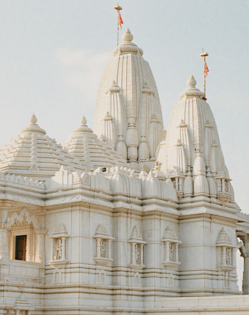 White marble Birla Mandir temple in India with intricate carvings, tall spires, and ornate pillars glowing in soft daylight against a clear sky thumbnail