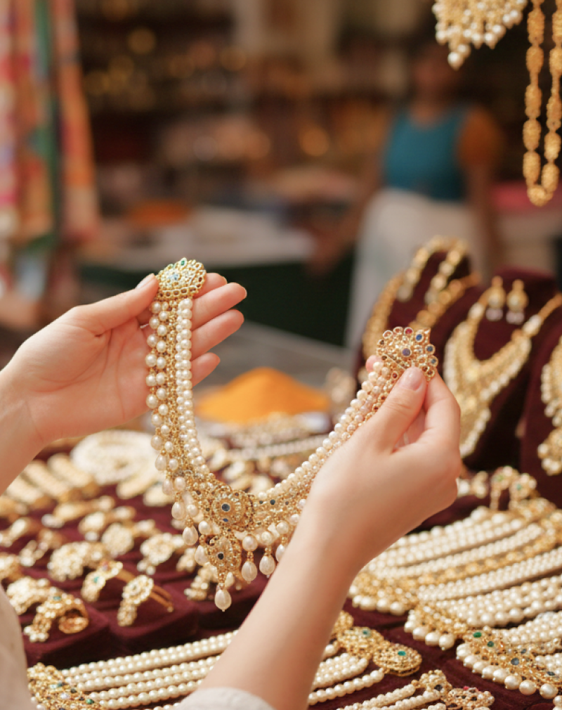 woman holding up pearl and gold necklace thumbnail