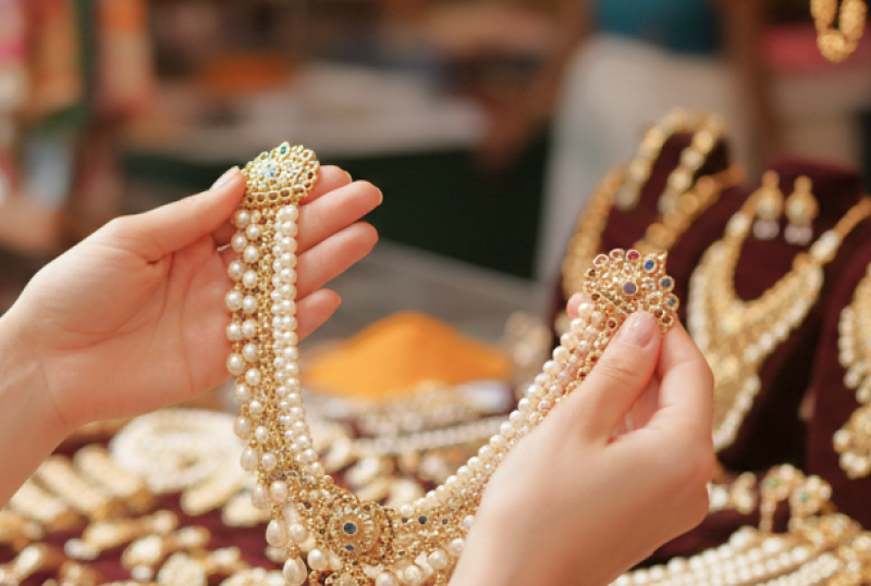 woman holding up pearl and gold necklace thumbnail