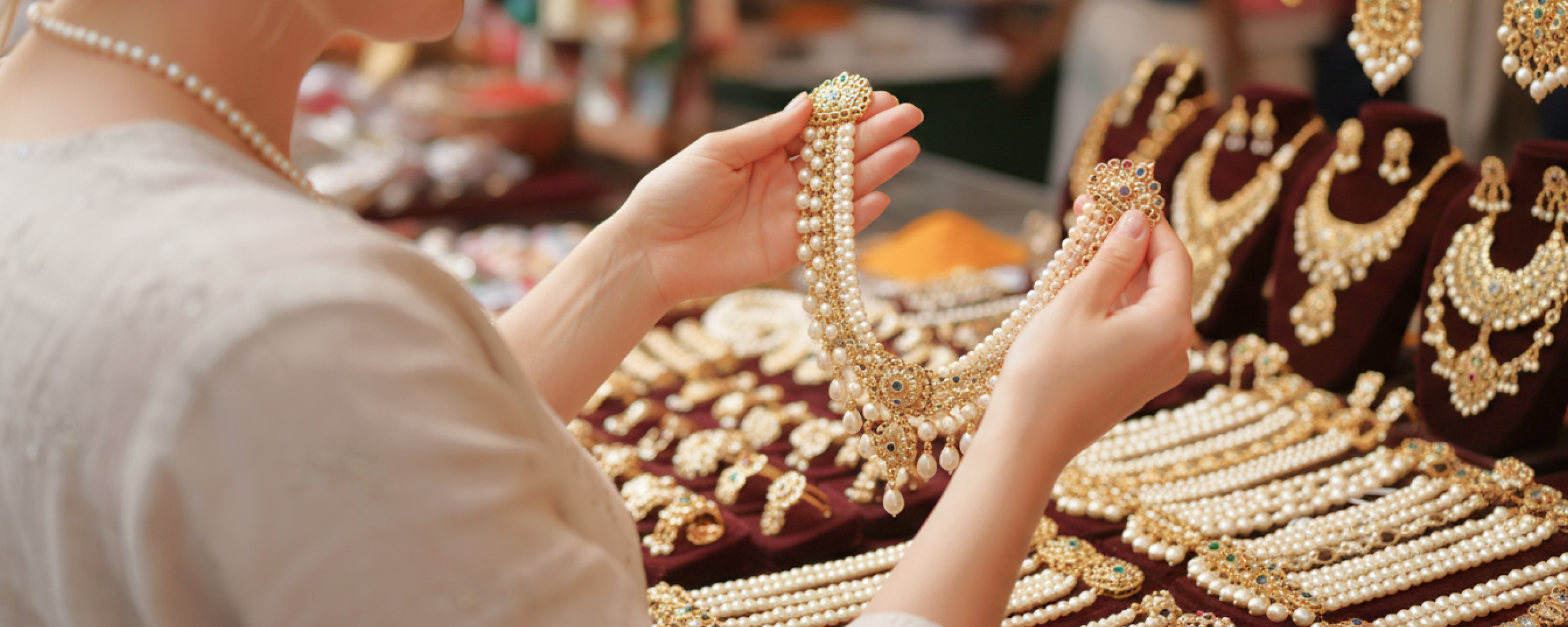 woman holding up pearl and gold necklace