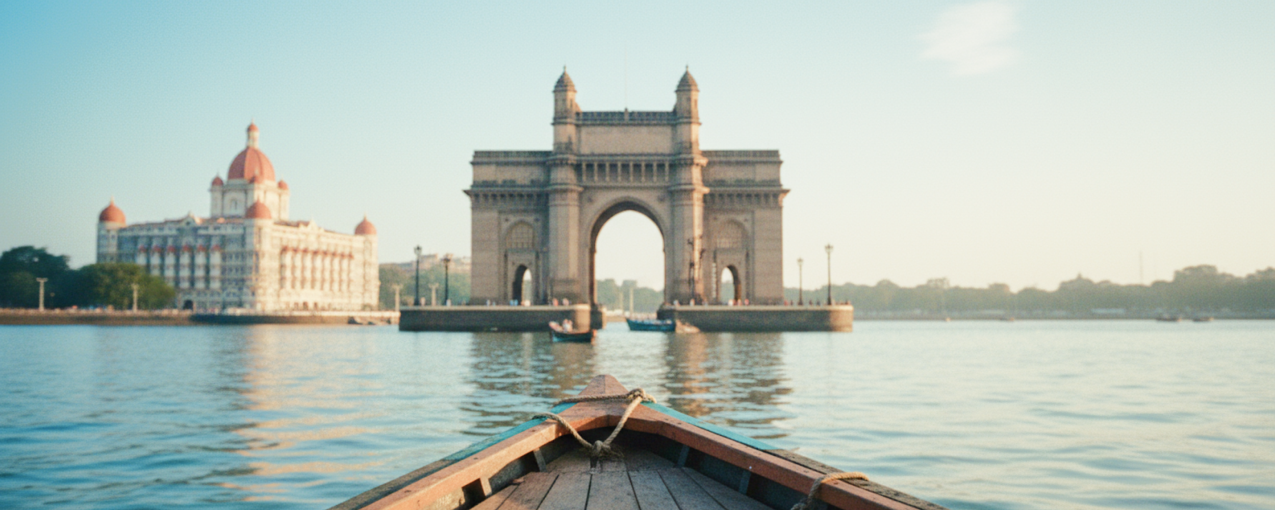 Boat's eye view of the Gateway of India and Taj Mahal Palace on the Mumbai travel guide, harbour glowing in early morning light