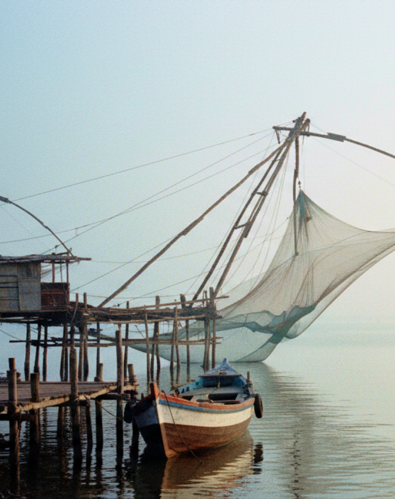 Chinese fishing nets and a weathered wooden boat on the misty Fort Kochi waterfront at dawn — a highlight of any day Kochi itinerary thumbnail