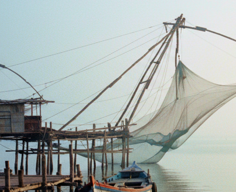 Chinese fishing nets and a weathered wooden boat on the misty Fort Kochi waterfront at dawn — a highlight of any day Kochi itinerary thumbnail