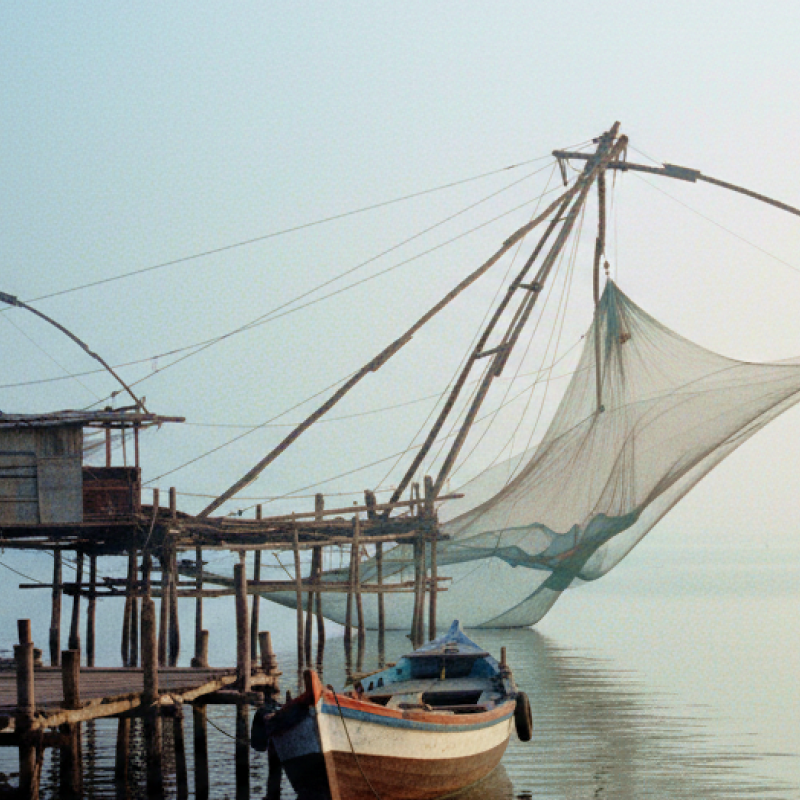 Chinese fishing nets and a weathered wooden boat on the misty Fort Kochi waterfront at dawn — a highlight of any day Kochi itinerary thumbnail