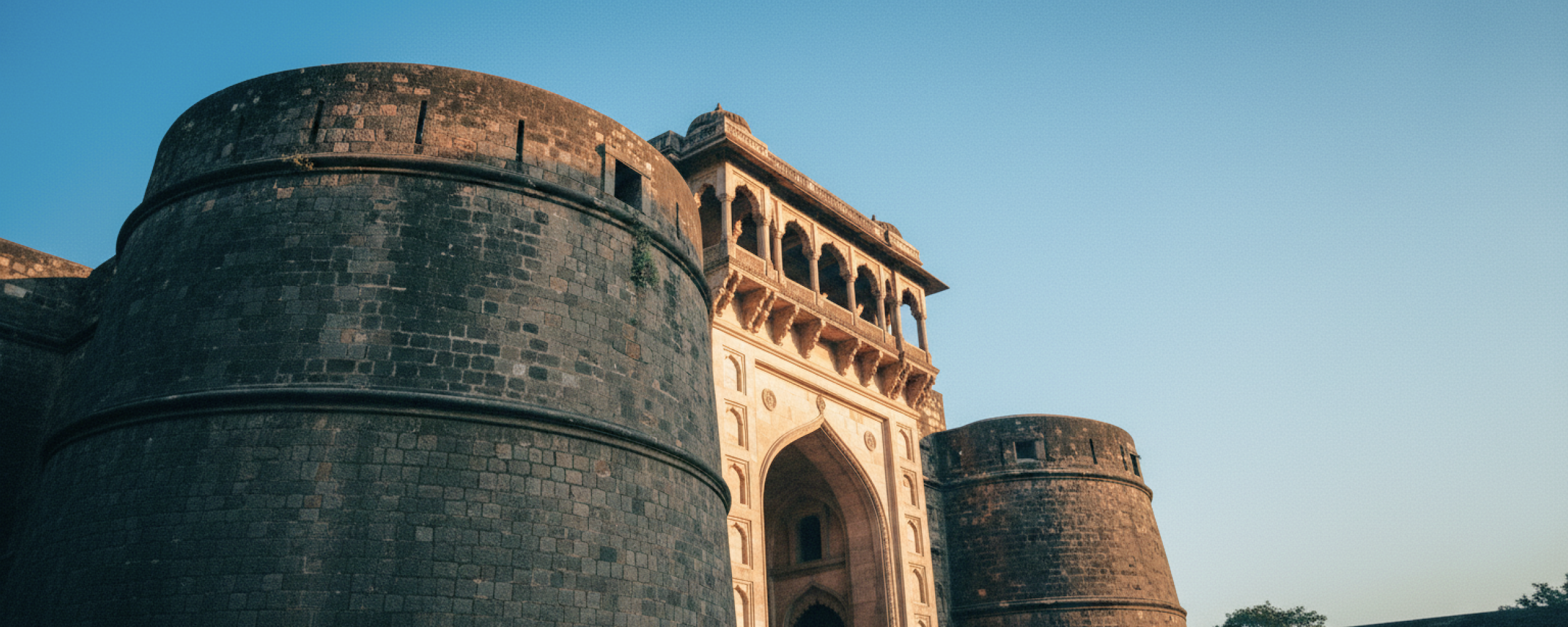 Low angle view of Shaniwar Wada's rounded bastion and colonnaded gateway at golden hour — an iconic landmark in any Pune travel guide