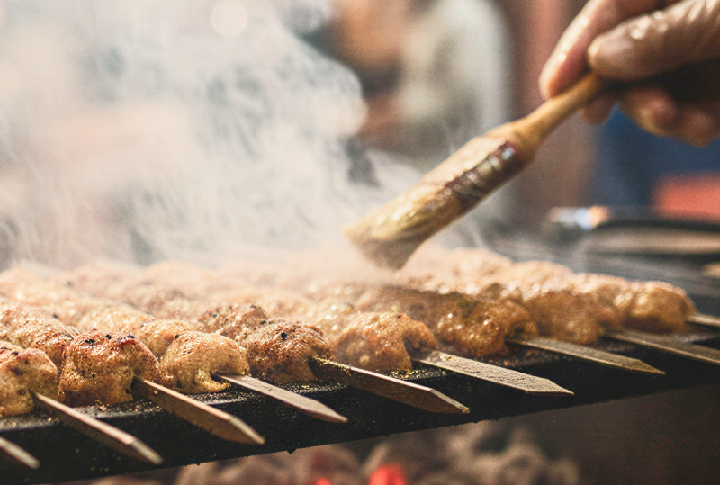 Smoky skewers of the best kebabs in Lucknow being basted over glowing charcoal at a busy street food stall thumbnail