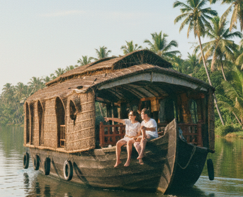Two tourists on a traditional houseboat drifting through the palm lined backwater canals near Kochi — a must do experience covered in this Kochi travel guide thumbnail