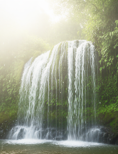 A magnificent waterfall in Meghalaya cascading into a misty jungle pool, surrounded by lush tropical greenery. a breathtaking natural sight to discover in India in June and July thumbnail