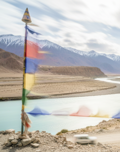 Tibetan prayer flags flutter over the turquoise Indus River winding through Ladakh's Himalayan landscape perfect for India summer travel thumbnail